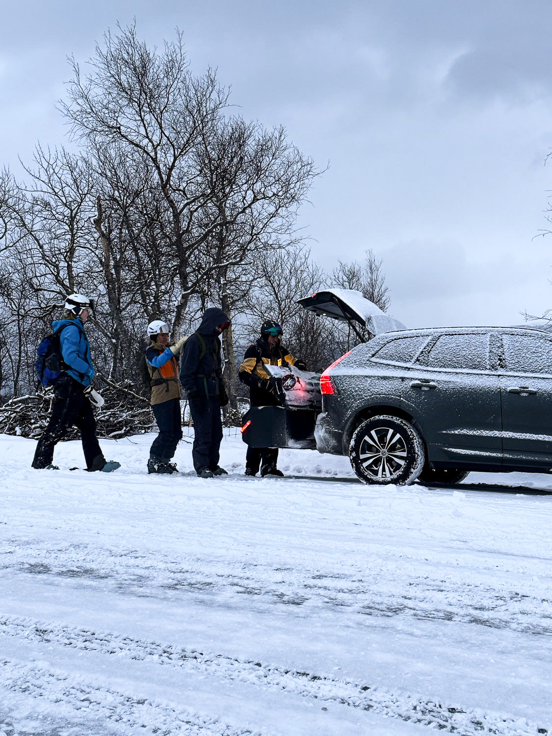 Car with an IXTAbox cargo box on the towbar in a winter landscape with skiers